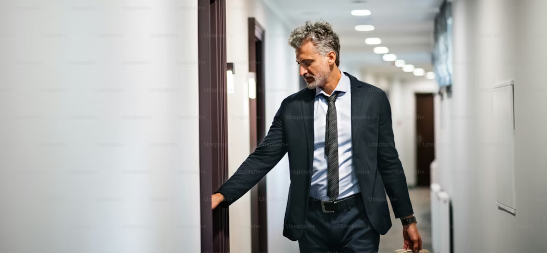 Businessman pulling a suitcase while walking through a hotel corridor, Intercity Chauffeur Routes